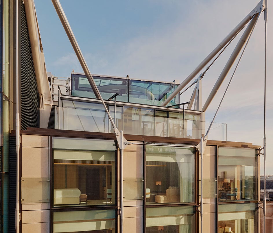 A striking architectural view of The Emory’s modern glass façade, featuring cantilevered terraces and sleek structural supports, bathed in the golden glow of the evening sun.