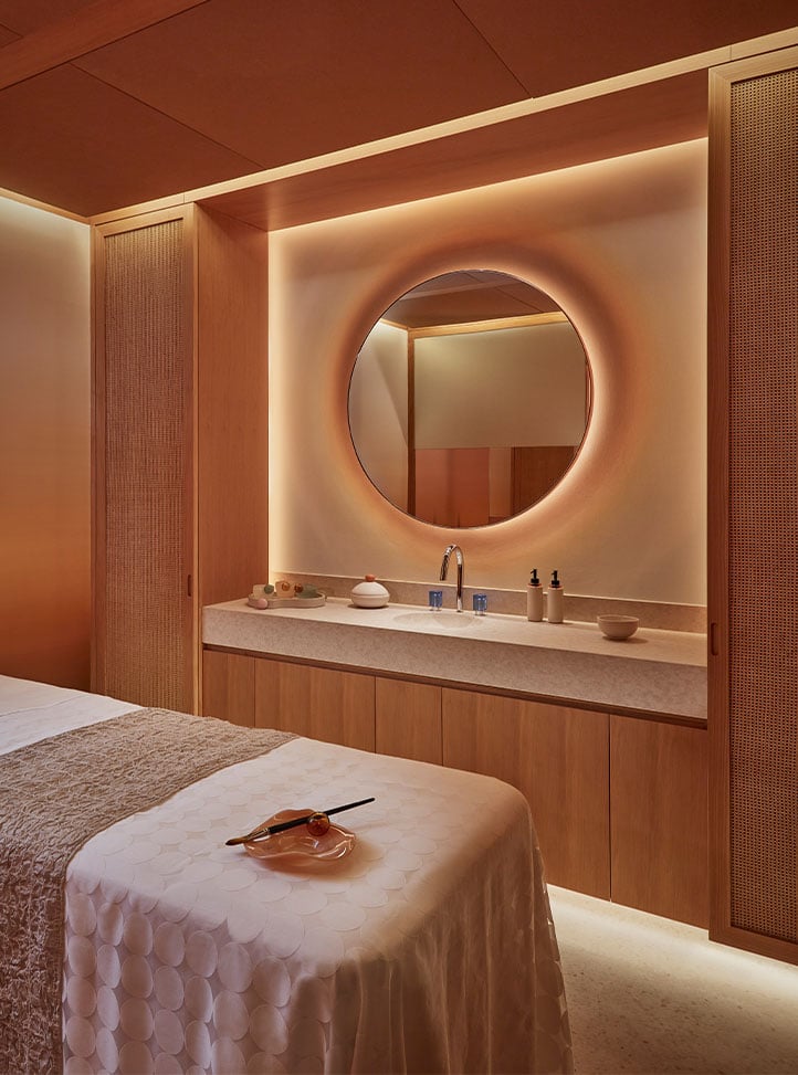 A serene spa setting featuring a plush massage table, ambient lighting, and elegant wooden cabinetry, designed for ultimate relaxation.