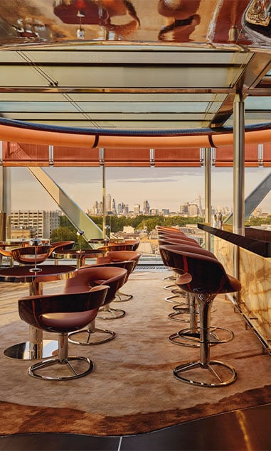 A sleek rooftop bar featuring modern seating and panoramic views of the London skyline.