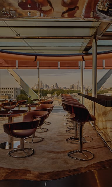 A sophisticated lounge with plush leather seating, an onyx bar, and floor-to-ceiling windows offering a stunning cityscape view, creating an elevated and refined ambiance.